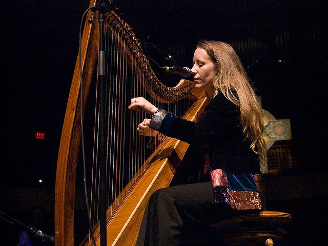 Kelly playing the harp in a concert hall